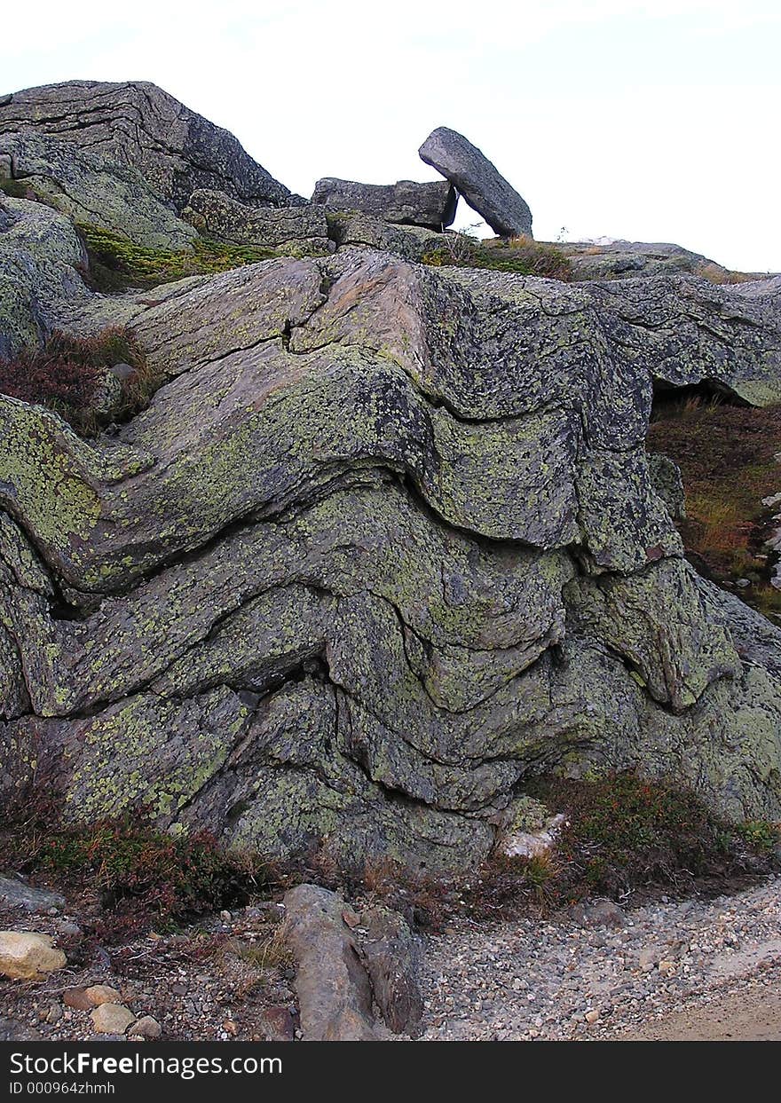 Geologic layers of mountain rock with glacier deposit on top