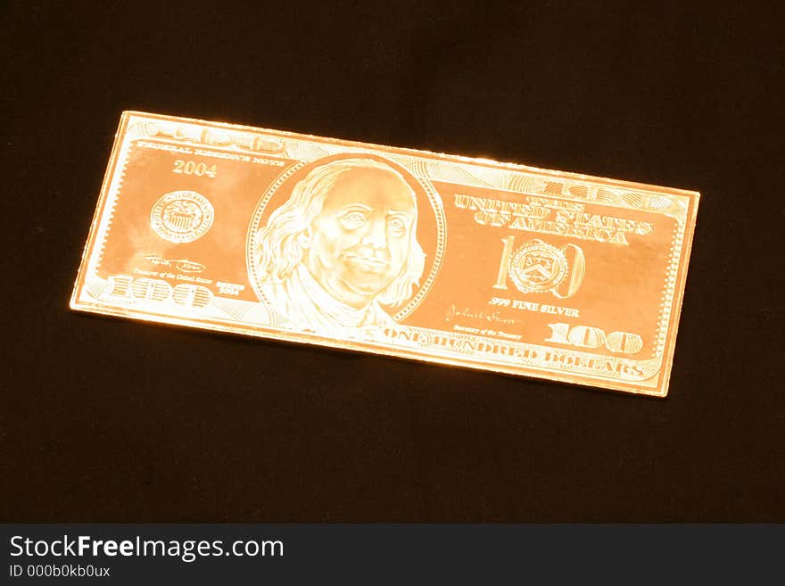 A silver proof of a United States hundred dollar bill in golden tones appearing to be superhot. A silver proof of a United States hundred dollar bill in golden tones appearing to be superhot.