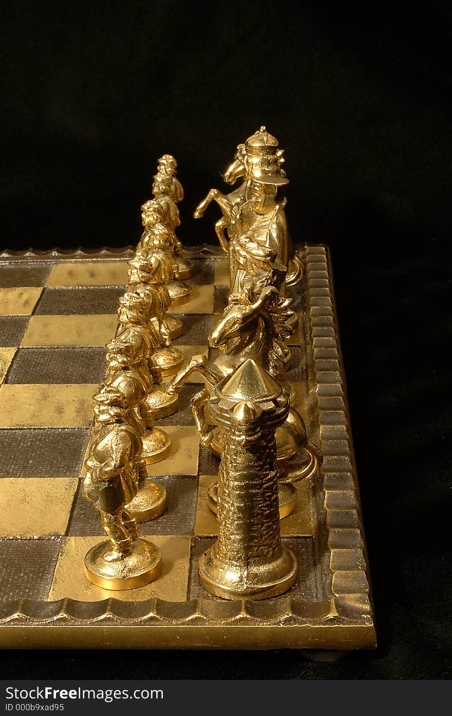 Closeup of an unique chess board with brass (white) side lineup. Very deep DOF so that all the pieces are in focus. Black background. Closeup of an unique chess board with brass (white) side lineup. Very deep DOF so that all the pieces are in focus. Black background.