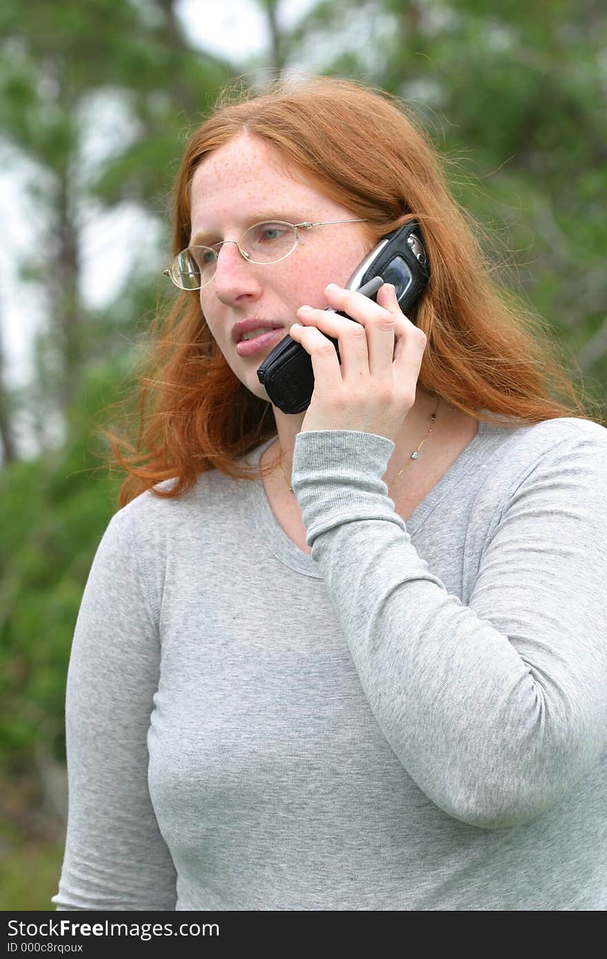 A redheaded woman in a gray long sleeved shirt gets some bad news on the phone. A redheaded woman in a gray long sleeved shirt gets some bad news on the phone.