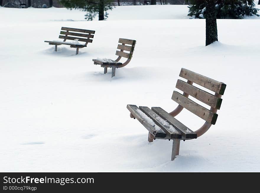 3 park benches in a snow covered park. 3 park benches in a snow covered park