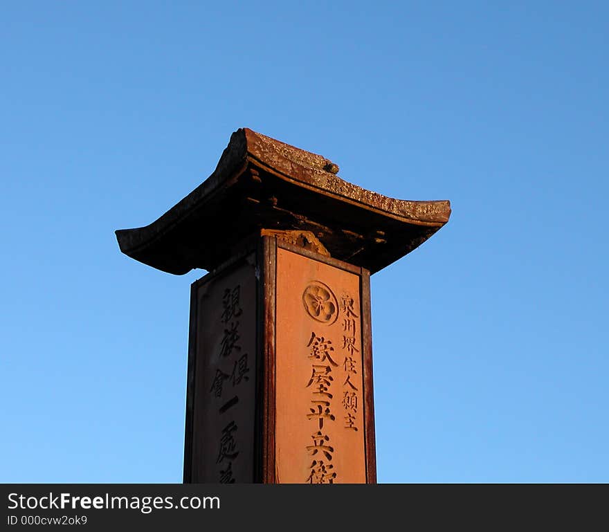 A funeral stone in a Japanese graveyard,over the sky background.The inscriptions have a religious character.