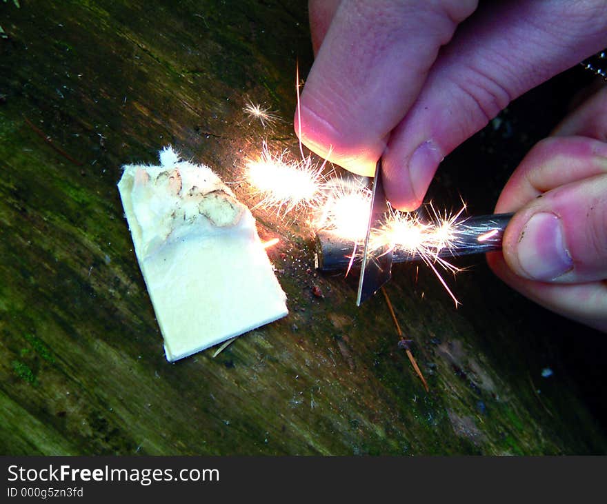 Close up shot of piece of tinder being lit by flint and striker. Close up shot of piece of tinder being lit by flint and striker