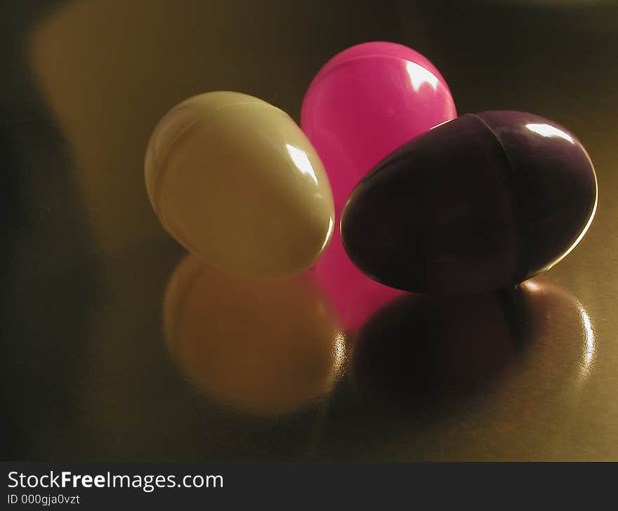 Colorful plastic Easter eggs, with a single light source from the side, on a metallic gold background. A modern, abstract sort of Easter image. Colorful plastic Easter eggs, with a single light source from the side, on a metallic gold background. A modern, abstract sort of Easter image.