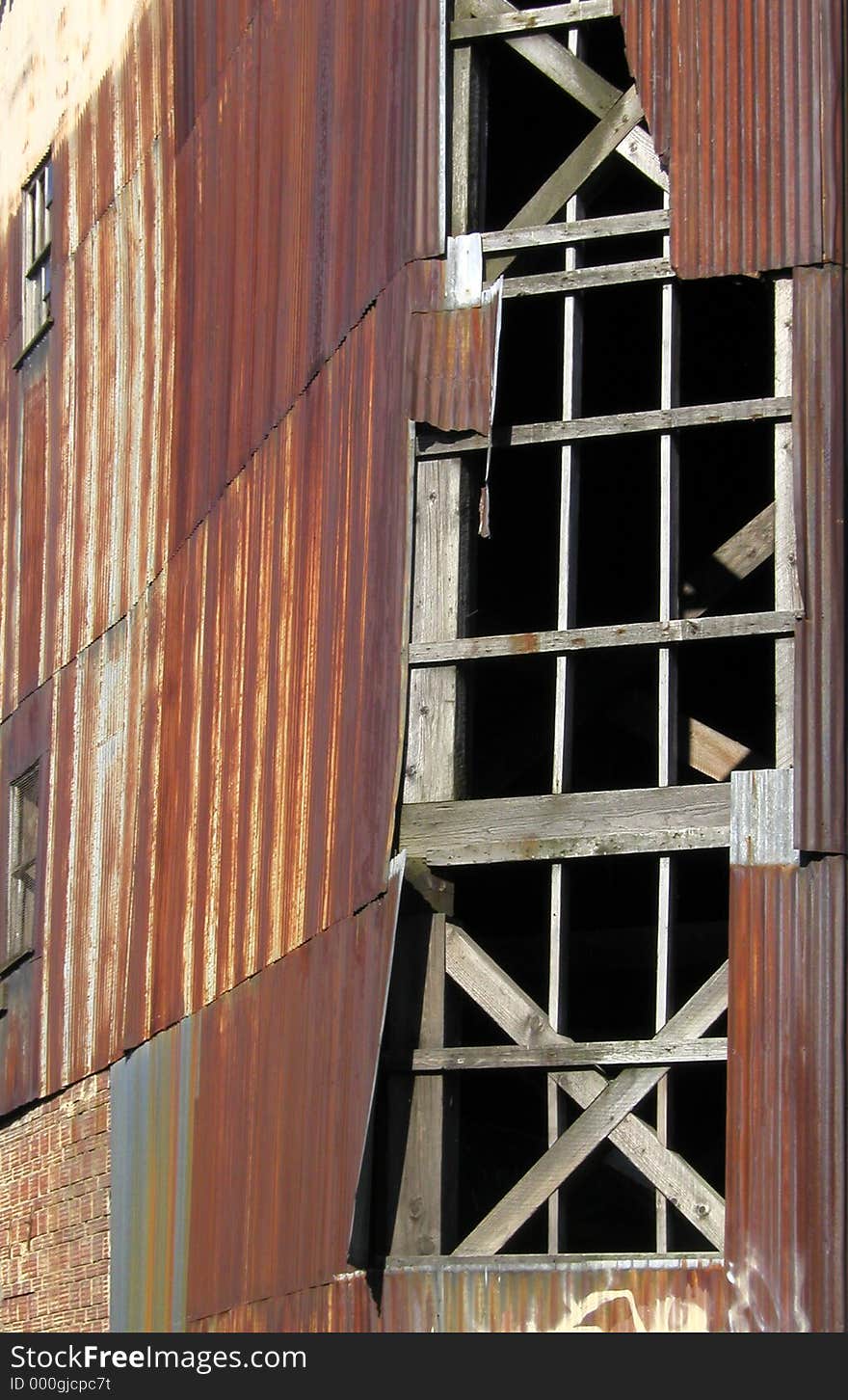 Section of an old warehouse with rusty corrugated siding and gaping, broken windows. Section of an old warehouse with rusty corrugated siding and gaping, broken windows.