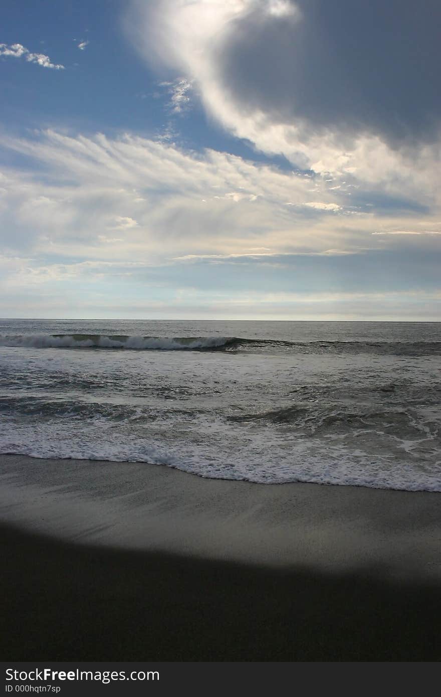 Rolling waves on the beach while whispy clouds dance above. Rolling waves on the beach while whispy clouds dance above