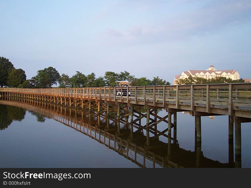 This was a picture taken on a golf course overlooking a calm creek and bridge. This was a picture taken on a golf course overlooking a calm creek and bridge