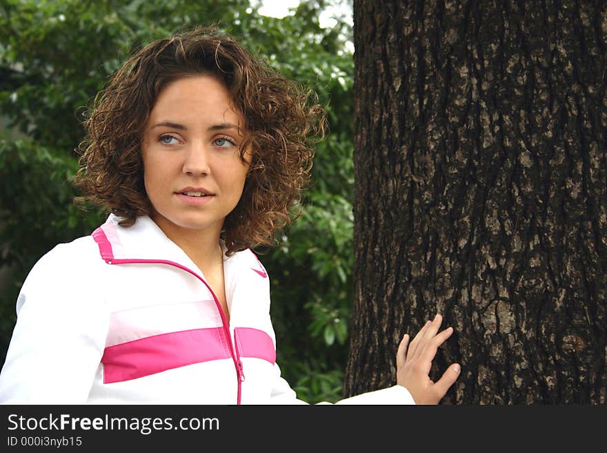 Teenage girl looking away while leaning on tall pine tree. Teenage girl looking away while leaning on tall pine tree