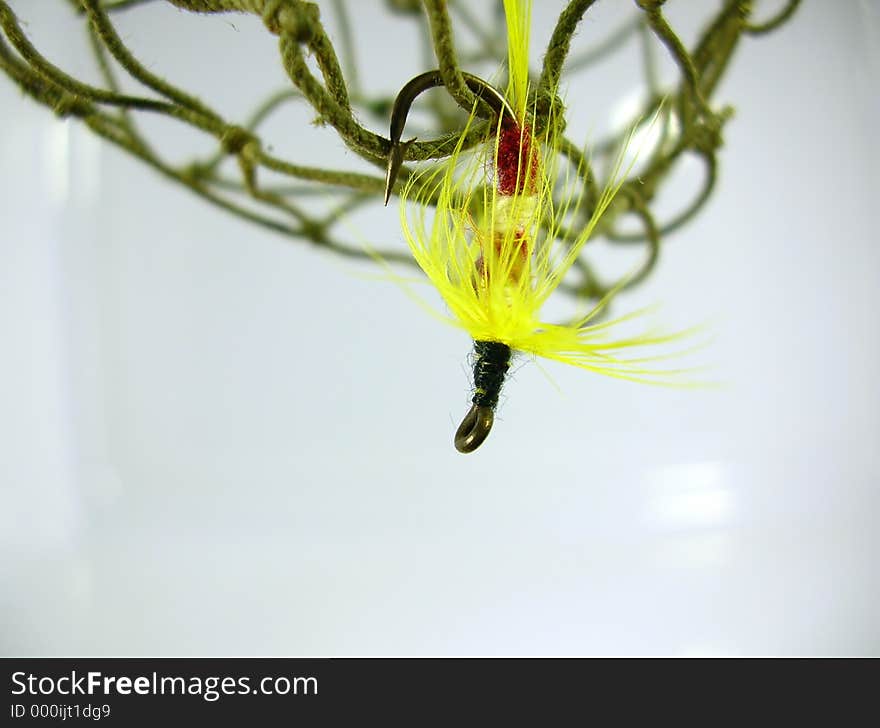 Macro of a yellow trout fly hanging from a fishing net. Macro of a yellow trout fly hanging from a fishing net.