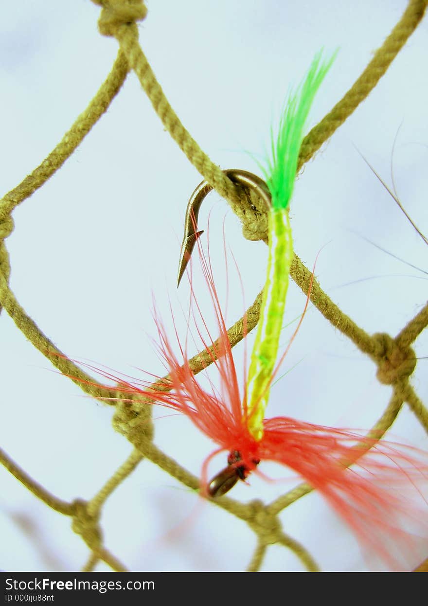 Single trout fly close-up hooked on fishing net. Single trout fly close-up hooked on fishing net.