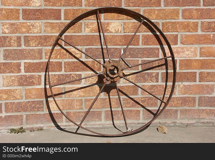 Old iron wheel leaning on a brick wall. Old iron wheel leaning on a brick wall