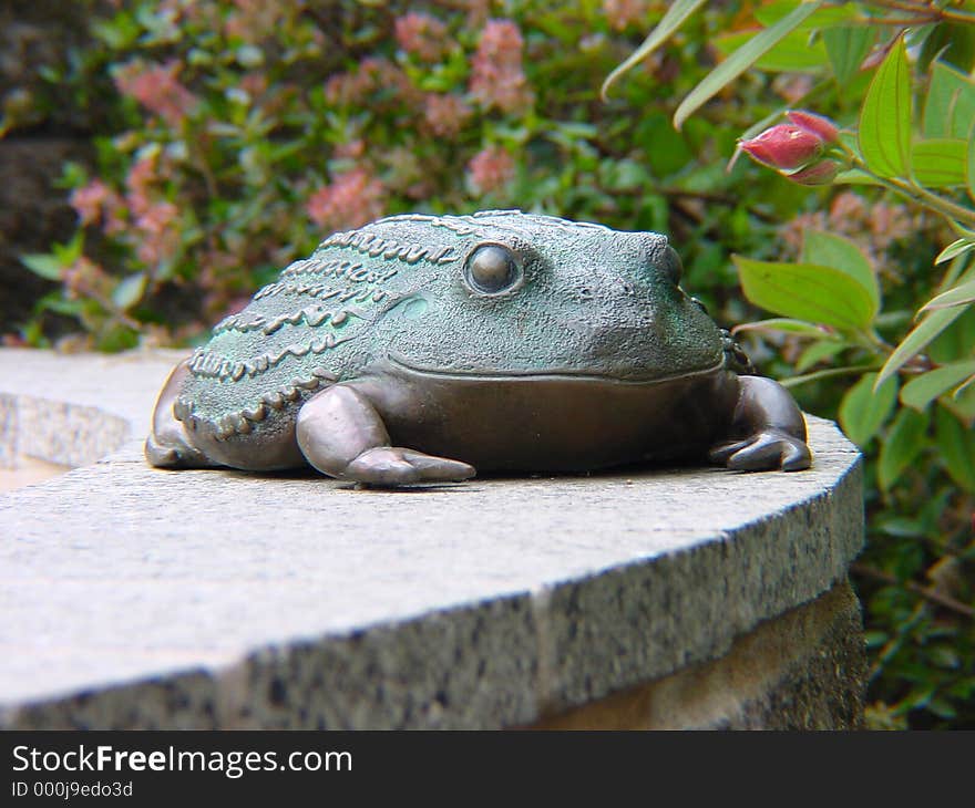 Frog statue sitting on a ledge.