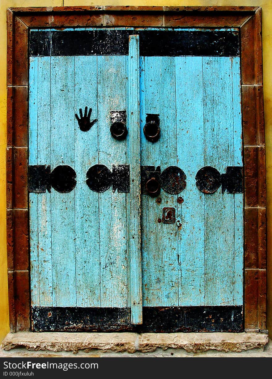 Old wooden door painted light blue with black metal decorations. Old wooden door painted light blue with black metal decorations