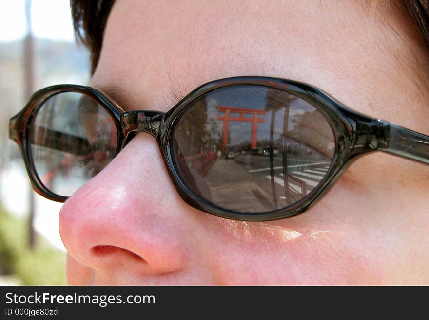 Reflection of a big Japanese temple gate in a tourist woman sunglasses