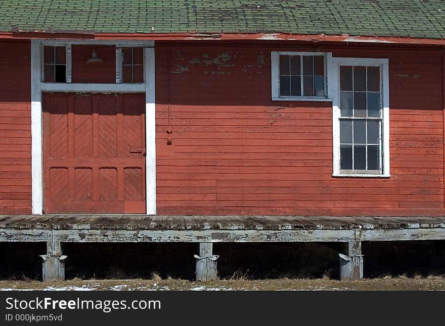 An old platform for unloading trains into the rail stop. Building is painted red with white trim. Dock door and a window are shown in photo. An old platform for unloading trains into the rail stop. Building is painted red with white trim. Dock door and a window are shown in photo.