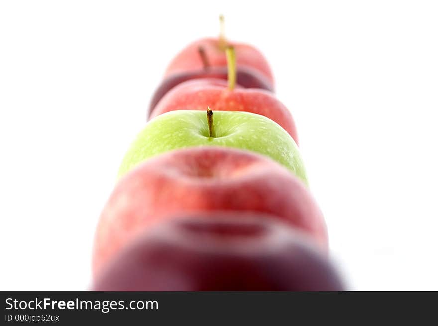 A green apple in a line of red. A green apple in a line of red