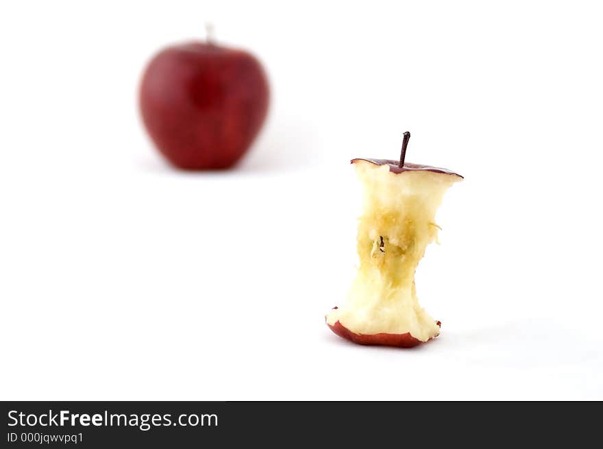 An apple core with an out of focus apple in the background