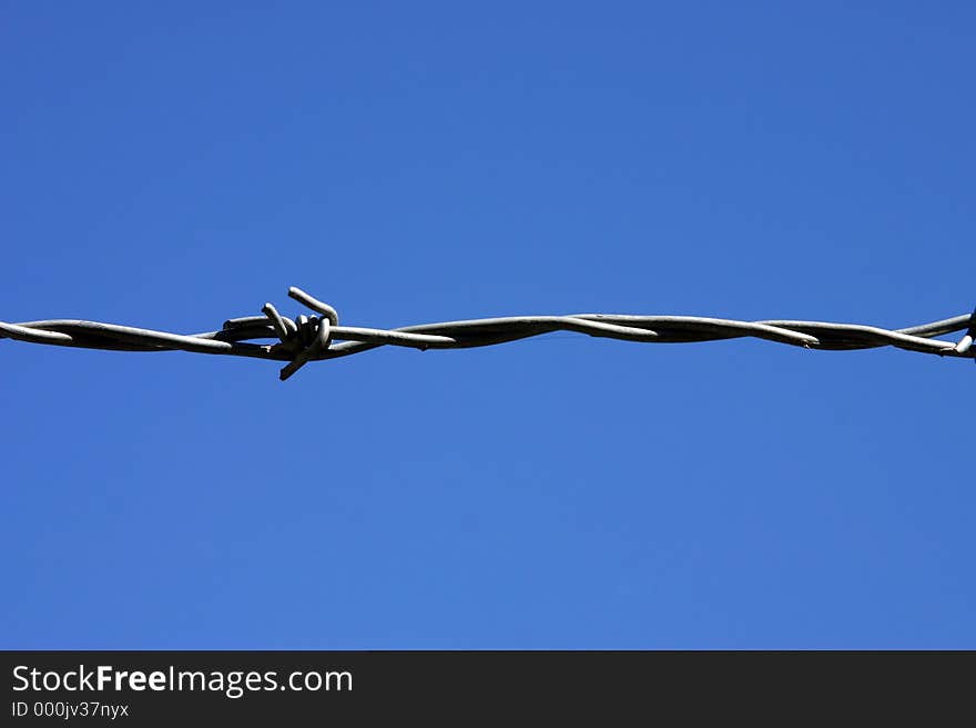 One strand of barbed wire in front of a great blue sky. One strand of barbed wire in front of a great blue sky.