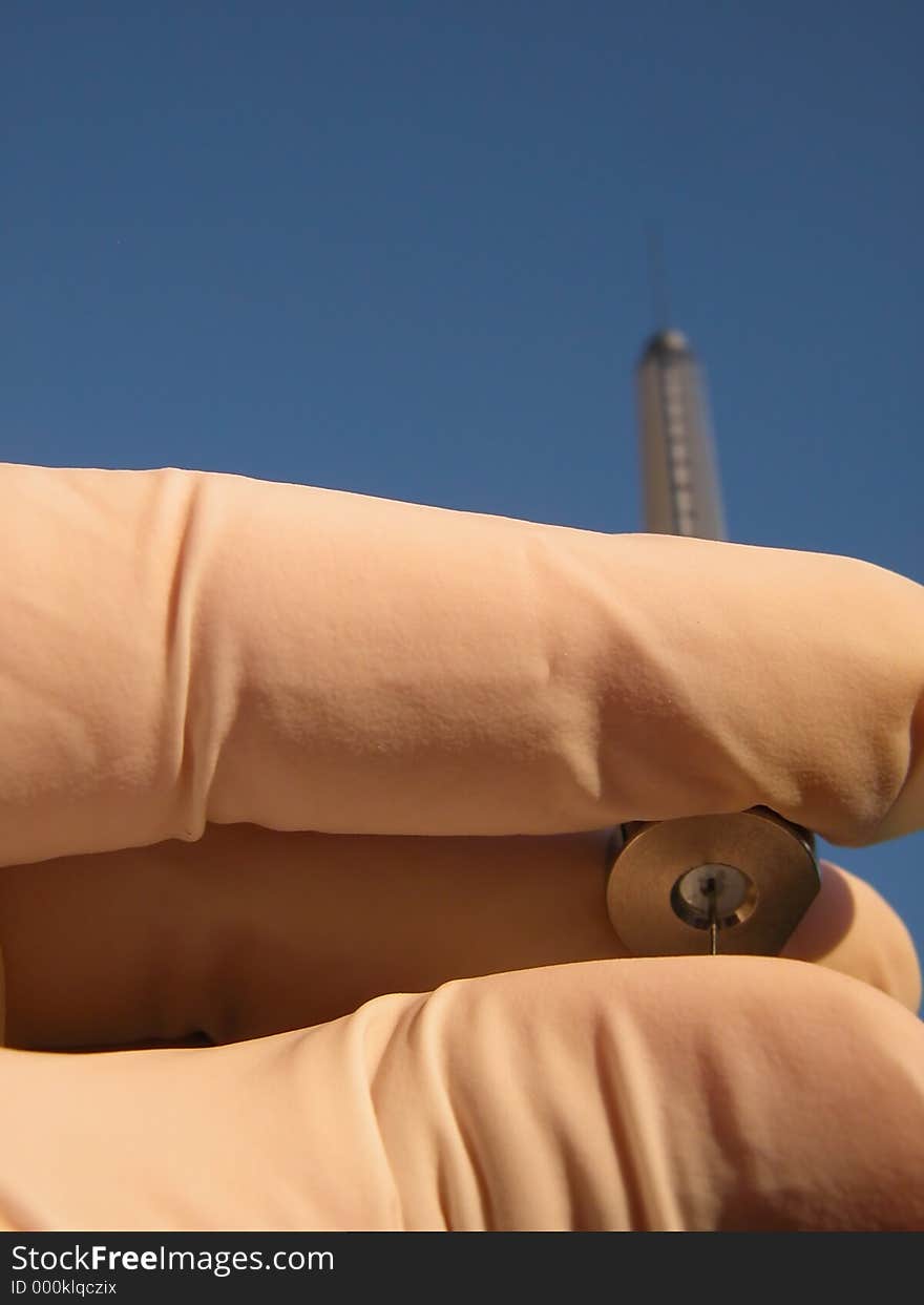 Close up of hand holding a syringe directed toward a blue sunny sky. Hand is protected with white glove, focus on the fingers. Possible use in: environmental protection, succes, aspiration, endeavour... or any websites/catalogs related to chemistry/medical design. Close up of hand holding a syringe directed toward a blue sunny sky. Hand is protected with white glove, focus on the fingers. Possible use in: environmental protection, succes, aspiration, endeavour... or any websites/catalogs related to chemistry/medical design