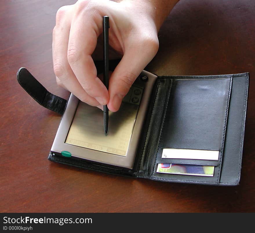 Man working on a pda on a wood desk, hand only. Man working on a pda on a wood desk, hand only.