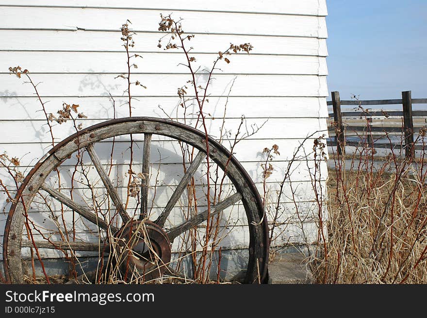 Old antique wagon wheel out front of farm building.