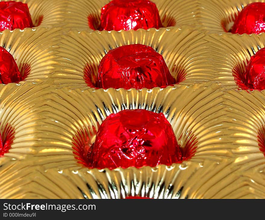 Red foil wrapped chocolates in gold tray. Red foil wrapped chocolates in gold tray