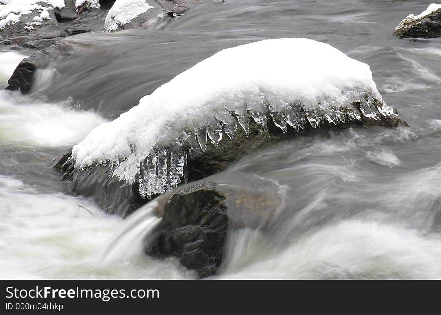 A small snow-covered rock in a river. A small snow-covered rock in a river...