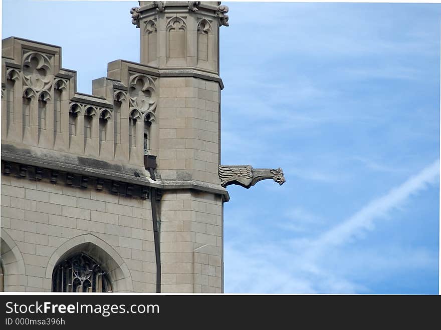 Partial view of an old stone cathedral showing stone work and a gargoyle water spout. Partial view of an old stone cathedral showing stone work and a gargoyle water spout.