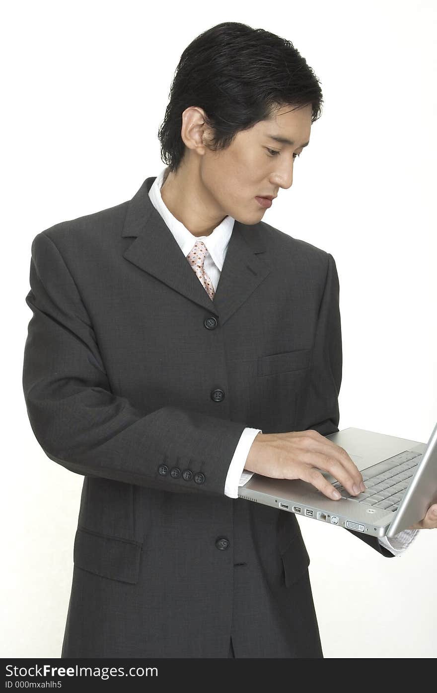 An asian businessman keeps up to date using his laptop computer. An asian businessman keeps up to date using his laptop computer