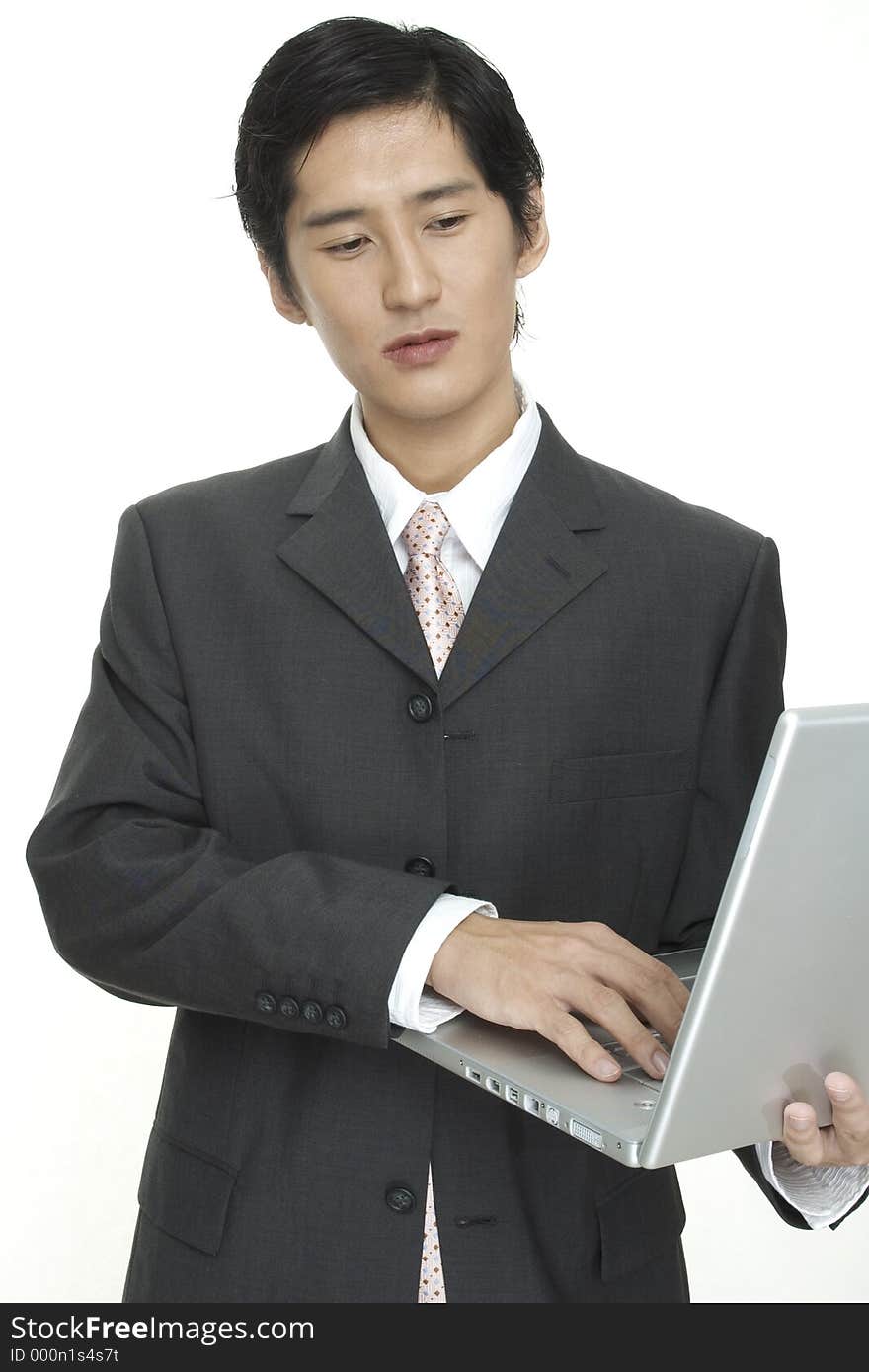 An asian businessman uses a laptop on the move. An asian businessman uses a laptop on the move