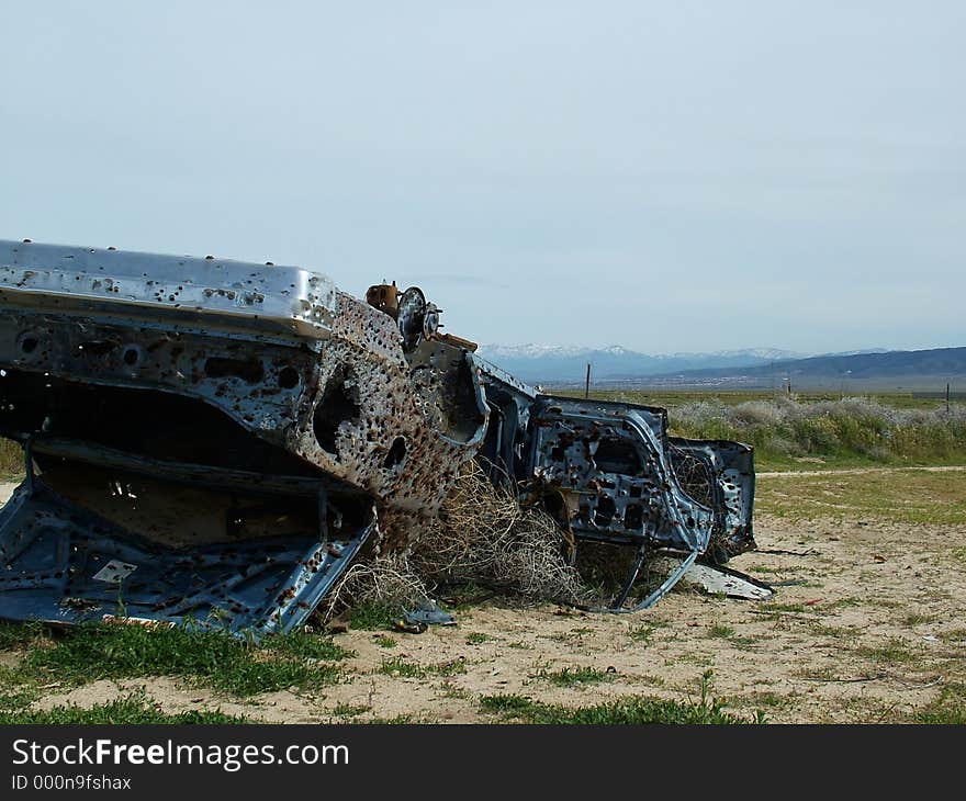 Overturned car, riddled with bullet holes in desert. Overturned car, riddled with bullet holes in desert