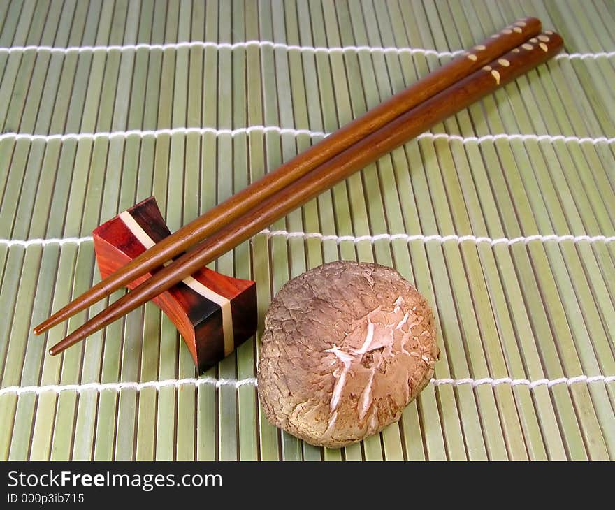 Chopsticks and mushroom over a bamboo background