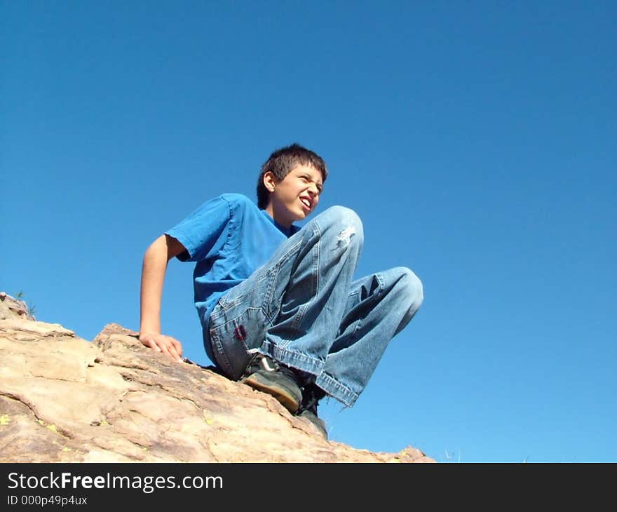 Boy on top of rock at Vasquez Rocks, California against bright blue sky. Boy on top of rock at Vasquez Rocks, California against bright blue sky