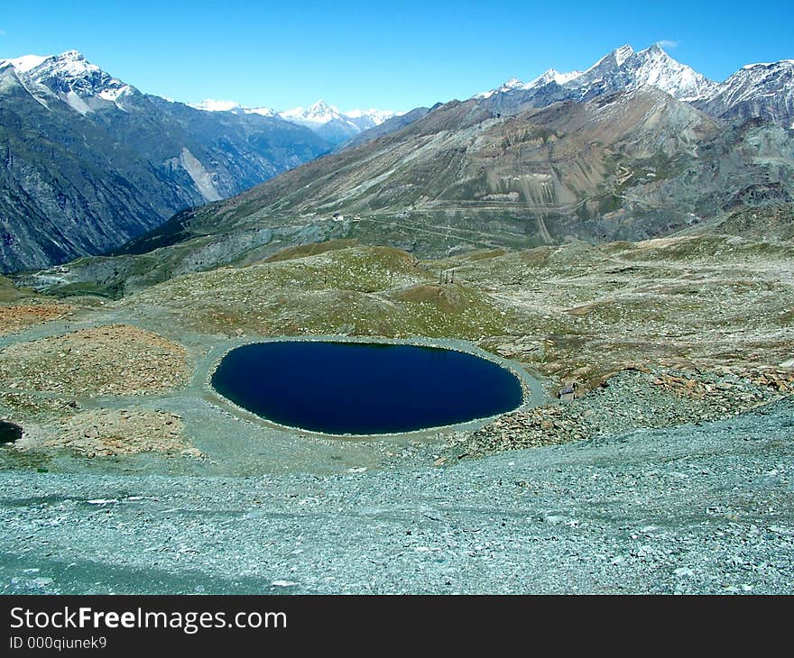 Digital photo of a little lake in the mountains/massif taken in switzerland in the alps. It looks like a landscape on the moon.