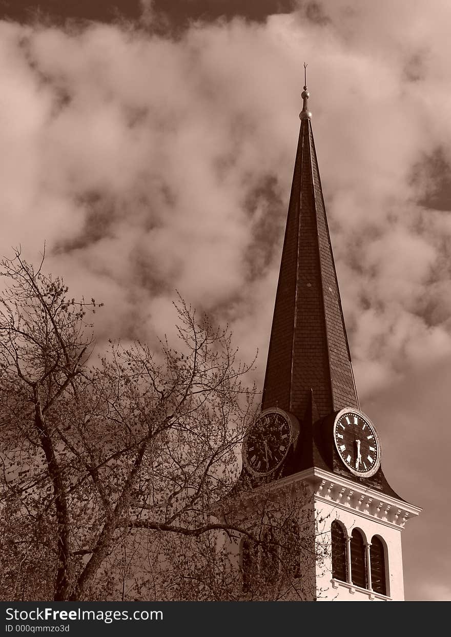 Sepia toned image showing steeple of old new england church in the spring time with tree in bloom and thick clouds