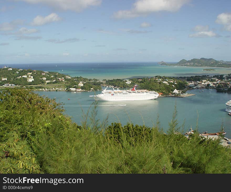 This cruise ship sits moored in a bay on a tropical island.