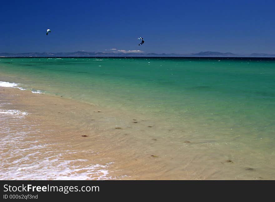 Beautiful sunny beach in southern Spain with kite surfers and Africa in the distance on a hot sunny day. Beautiful sunny beach in southern Spain with kite surfers and Africa in the distance on a hot sunny day.