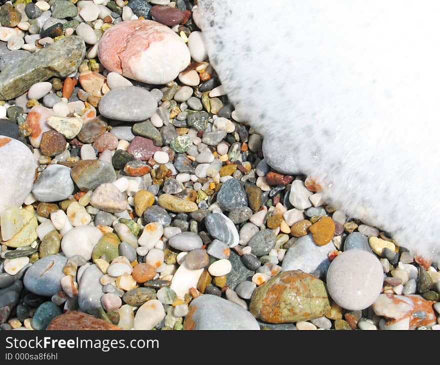 The foam of a wave as it is rushing in over the pebbles (close-up). The foam of a wave as it is rushing in over the pebbles (close-up)