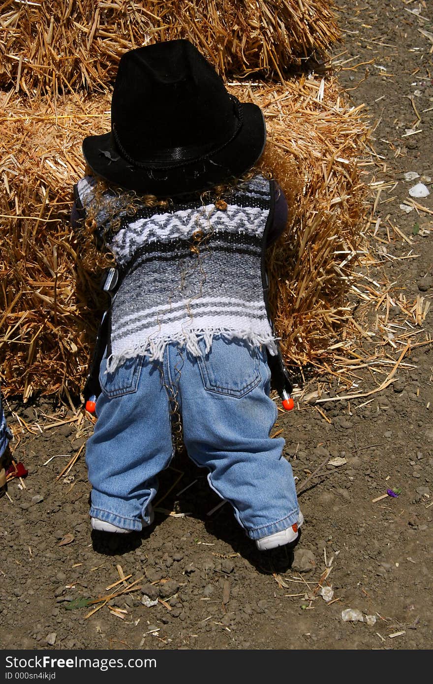 A toy doll dressed in farm clothing leans against a haystack at a farm in California. A toy doll dressed in farm clothing leans against a haystack at a farm in California.