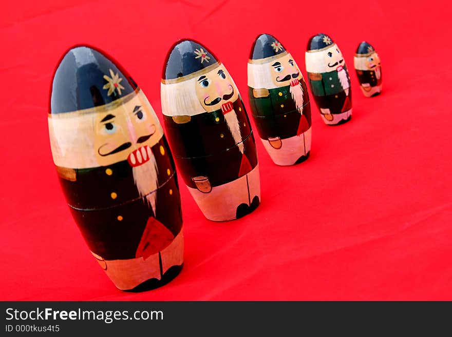 Russian nesting nutcrackers shot at an angle against a red background. Selective focus on the second nutcracker from left. Russian nesting nutcrackers shot at an angle against a red background. Selective focus on the second nutcracker from left.