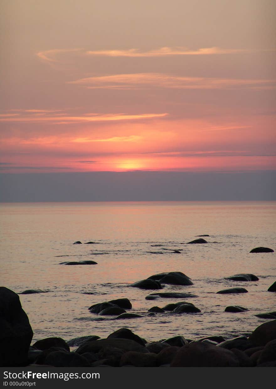 Senset on Baltic Sea. Red sun in going down and big stones lie quite