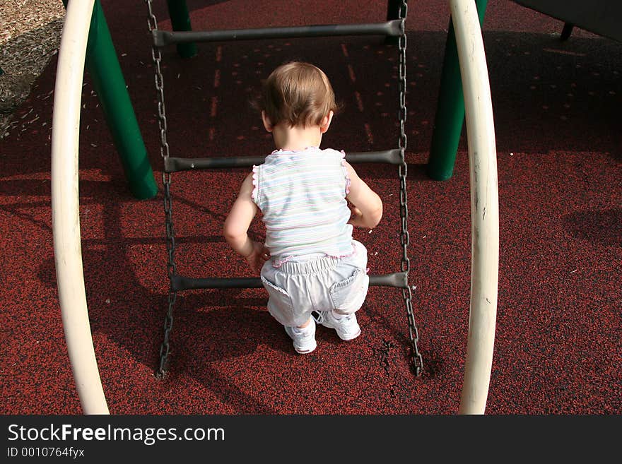Baby girl thinking about climbing bars at playground. Shot with a Canon 20D.