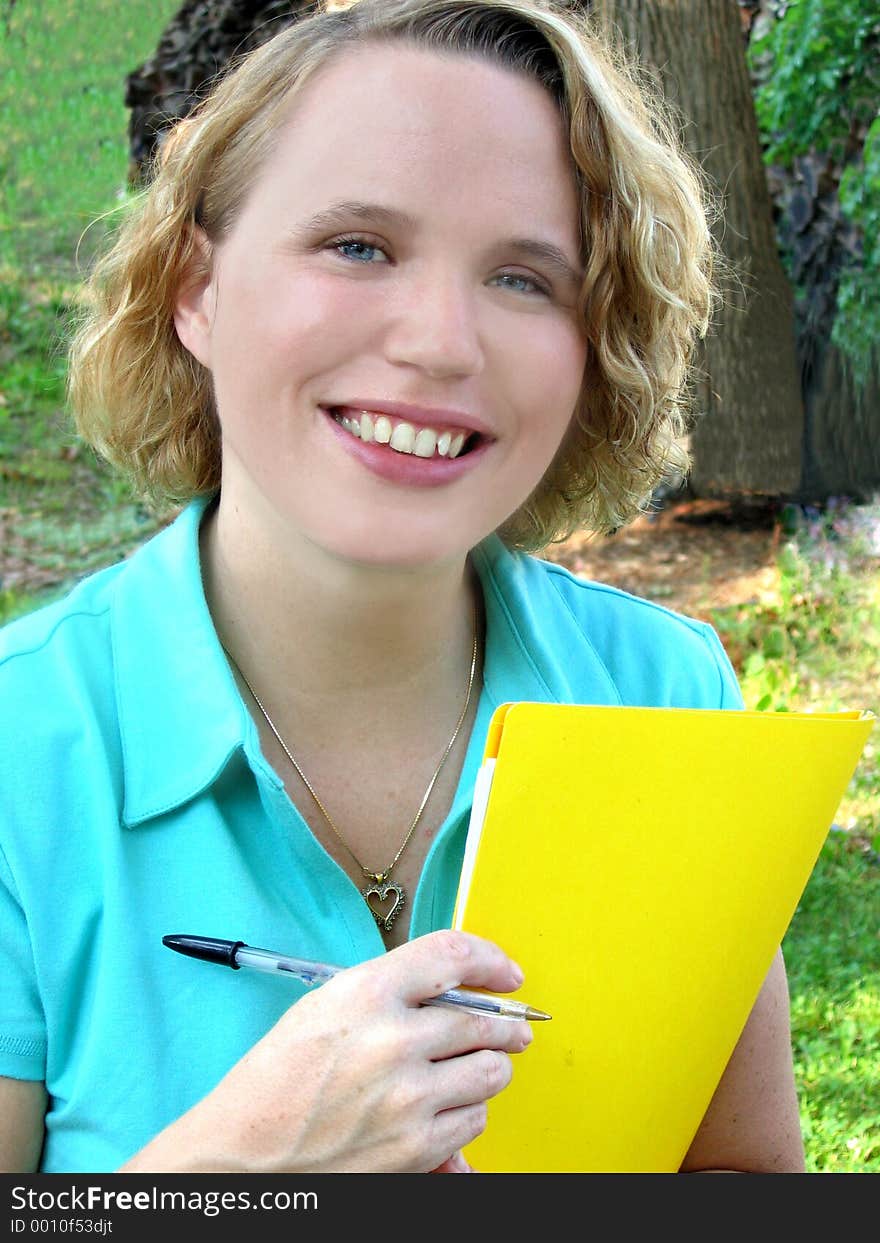 Attractive young woman outdoors with folder and pen