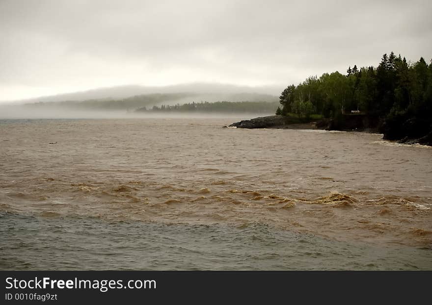 Flooded stream emptying into lake on a foggy day. Flooded stream emptying into lake on a foggy day