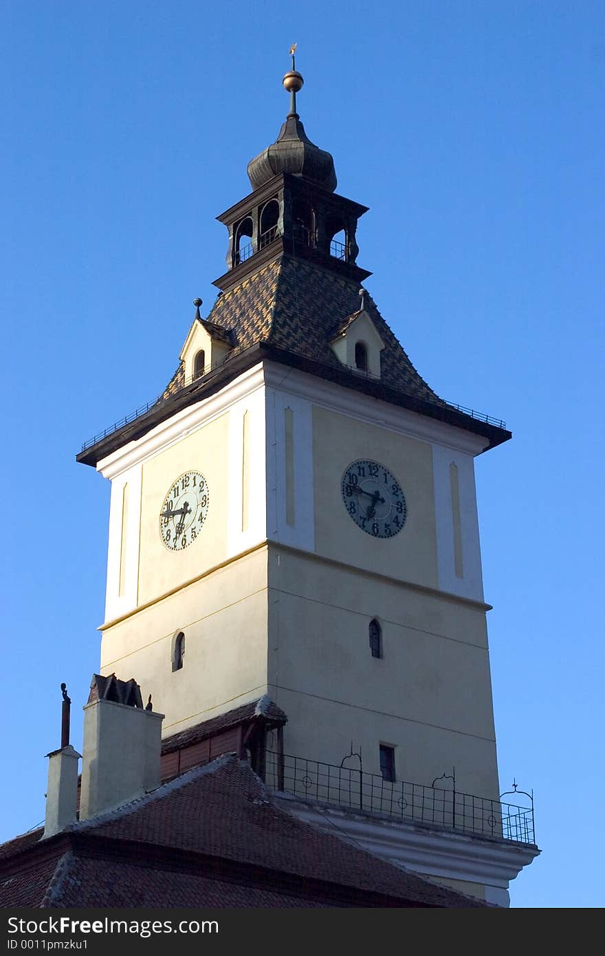 A square clock tower with a blue sky background