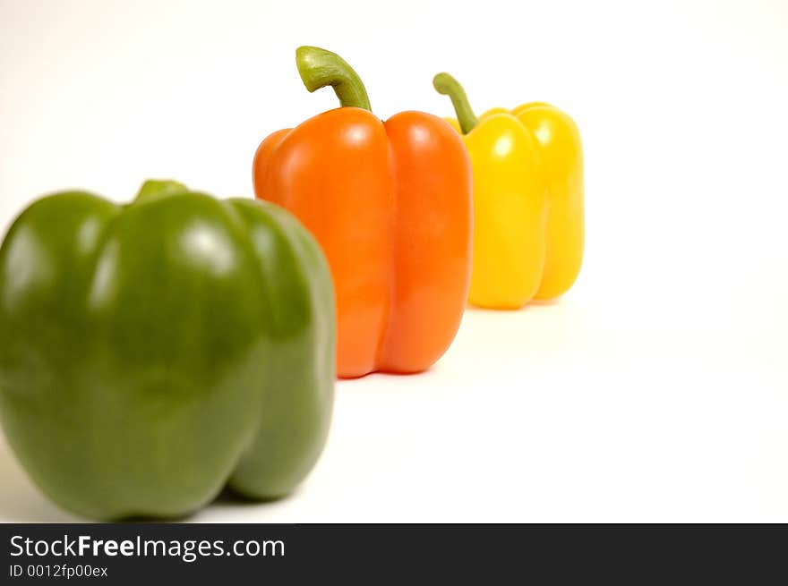 Green, yellow and orange paprika on a white background.