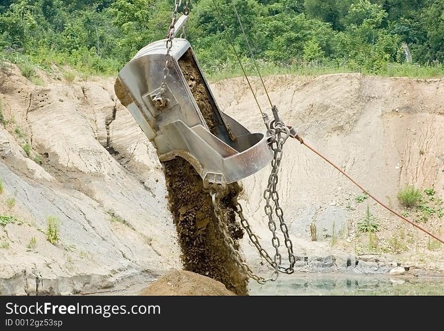 A large excavating bucket being dumped. A large excavating bucket being dumped.