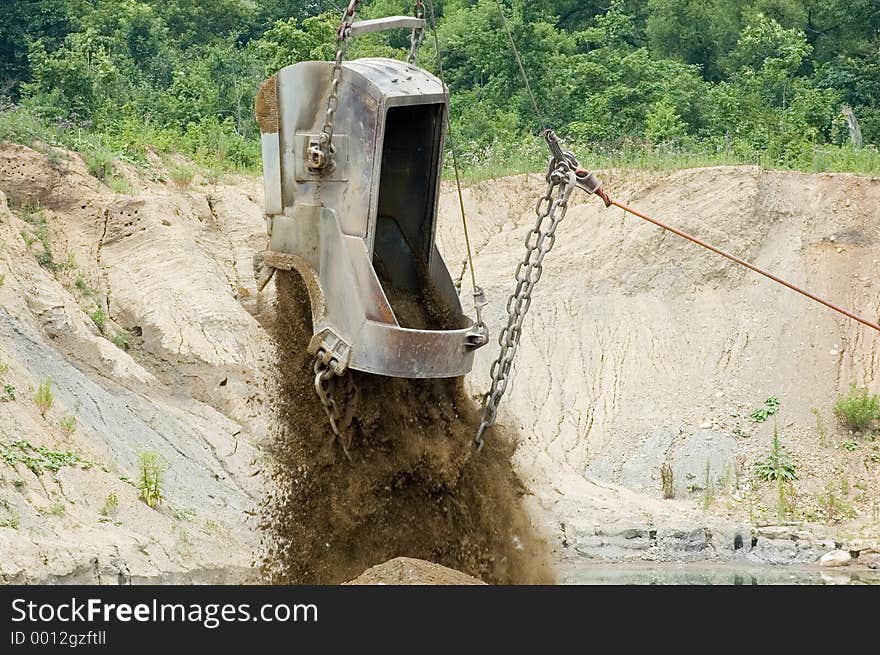 A large excavating bucket being dumped. A large excavating bucket being dumped