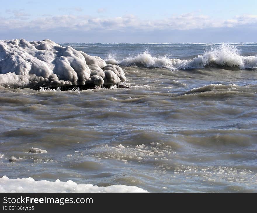 Ocean waves crash along an icy winter shoreline. Ocean waves crash along an icy winter shoreline.