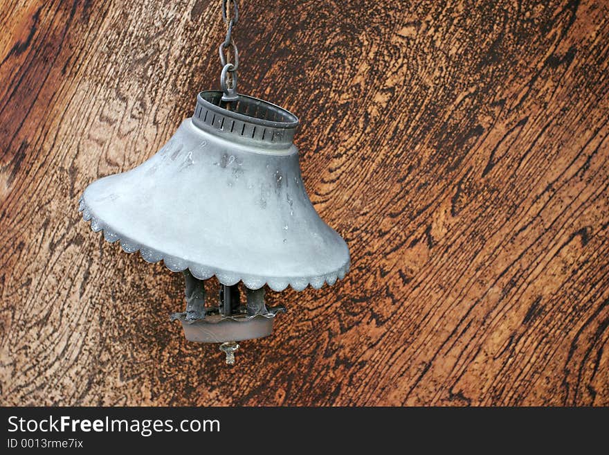 An old, broken electric lamp, hangs on a chain with its cooked shade. An old, broken electric lamp, hangs on a chain with its cooked shade.